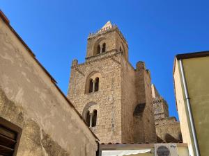 wysoki budynek z wieżą na szczycie budynku w obiekcie Rocca&Torre Houses w Cefalù