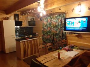 a kitchen with a table and a television on the wall at Domek Letniskowy - M & E in Warchały