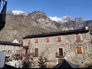 a large stone building with mountains in the background at CHECK-IN CASAS Labert in Benasque