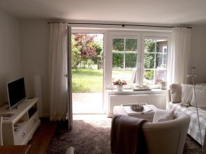 Una sala de estar con un sofá y una puerta corrediza de vidrio. en Haus Anneliese Bungalow Düne, en Norddorf