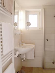 Un baño blanco con lavabo y espejo. en Haus Anneliese Bungalow Düne, en Norddorf