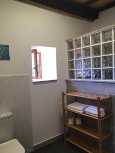 a bathroom with a toilet and a shelf with towels at O Fogar do Monte in Sober