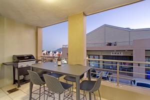 een eetkamer met een tafel en stoelen op een balkon bij Seaside Village by HostAgents in Kaapstad