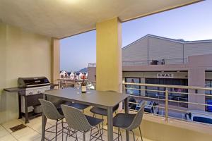 a dining room with a table and chairs on a balcony at Seaside Village by HostAgents in Cape Town