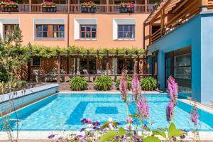 a swimming pool in front of a building with purple flowers at Hotel Montafoner Hof in Schruns