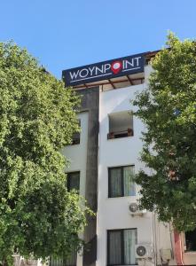 a sign on the side of a building with trees at Woynpoint Hotel&Cafe in Fethiye