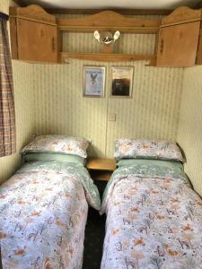 Lettoch Farm Holiday Home في دوفتاون: سريرين يجلسون بجانب بعض في غرفة النوم