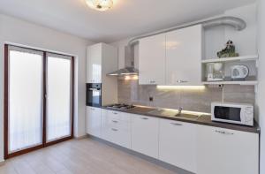 a kitchen with white cabinets and a microwave at House Pula 2080 in Pula