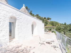 a white building with chairs and a table on a patio at Trulleria Alchimia in Selva di Fasano