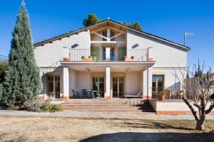 a white house with a porch and stairs in front at Xalet de la Muntanya El BrucMontserrat in El Bruc