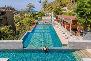 a man standing in the water in a swimming pool at Sunsuri Phuket - SHA Plus in Nai Harn Beach