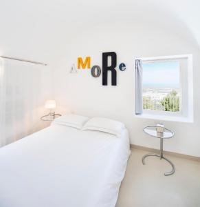 a white bedroom with a white bed and a window at Lamia Alchimia in Selva di Fasano