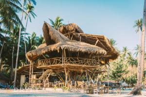 a straw hut on a beach with chairs and palm trees at Dryft Darocotan Island in El Nido