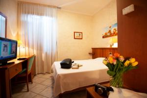 a hotel room with a bed and a vase of flowers at Hotel Corte Regina in Sirmione