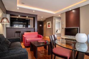 uma sala de estar com um sofá, uma mesa e uma televisão em Washington Parquesol Suites & Hotel em Valladolid