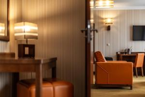 a hotel room with an orange chair and a desk at Dworek Morski SPA & Wellness in Mielno