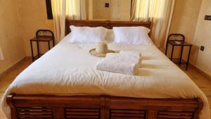 uma cama com duas toalhas e um chapéu em Le Beau Site Ourika em Aghmat