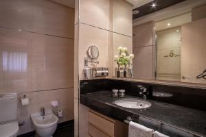 uma casa de banho com um lavatório, um WC e um espelho. em Washington Parquesol Suites & Hotel em Valladolid