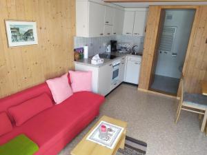 a living room with a red couch and a kitchen at 2 Zimmerwohnung Homestay Brienz Spanischgässli in Brienz