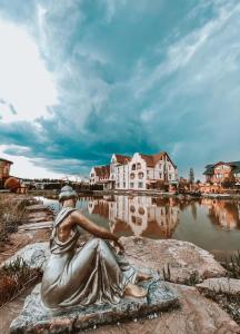 a statue of a woman sitting on a rock near a body of water at Berejki-Hall in Yegor'yevsk