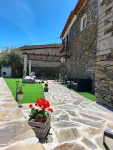 a stone patio with red flowers and a building at Casa Dona Eufémia in Pinhão