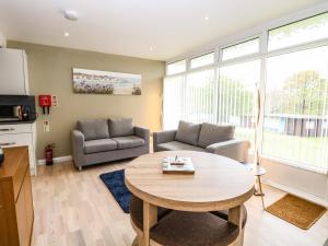 a living room with a table and a couch at Chalet 126a in Cromer +6 photos