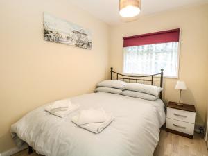 a bedroom with a bed with white sheets and a window at Chalet 126a in Cromer