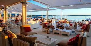 a group of people sitting on a patio near the water at Apartment Simunic Punta in Bibinje