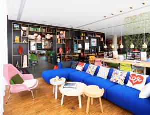 uma sala de estar com um sofá azul e cadeiras em citizenM Paris La Défense em Nanterre