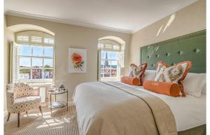 a bedroom with a bed and a chair and windows at Chichester Harbour Hotel and Spa in Chichester