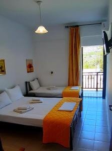 um quarto de hotel com duas camas e uma varanda em Platanos Rooms em Sinoikismós Kámbos