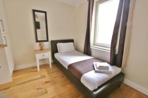 a small bed in a room with a window at Central Studios Gloucester Road by RoomsBooked - Free Parking in Cheltenham