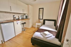 um pequeno quarto com uma cama e uma cozinha em Central Studios Gloucester Road by RoomsBooked - Free Parking em Cheltenham