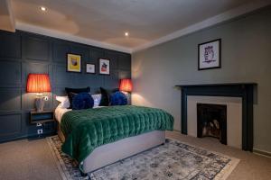 um quarto com uma cama verde e uma lareira em The Bell & Stuart House em Stow on the Wold