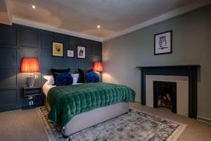 a bedroom with a green bed and a fireplace at The Bell & Stuart House in Stow on the Wold