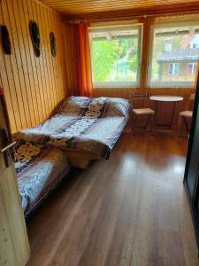 two beds in a room with a table and windows at Iza-pokoje do wynajecia in Wisełka