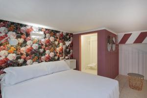 a bedroom with a white bed and a floral wall at Atelier Apartments by Wonderful Italy in Genoa