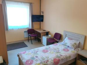 a bedroom with a bed and two chairs and a desk at Kambarių nuoma - Neveronys SAURIDA in Neveronys