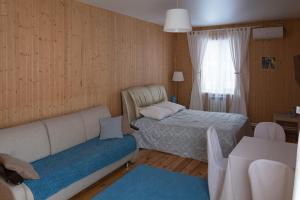 a bedroom with a bed and a couch and a window at Usadba Zhemchuznaya in Cheboksary