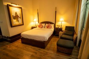 Habitación de hotel con cama y silla en Royal Orchid Brindavan Garden Mysore, en Belagula