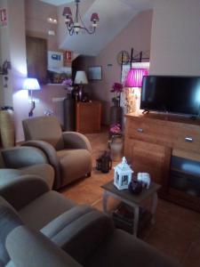 a living room with couches and a flat screen tv at Hostal Sol de la Vega in Albarracín