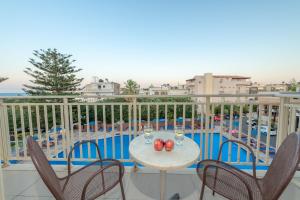 a table and chairs on a balcony with a pool at CHC Marilena Hotel in Amoudara Herakliou