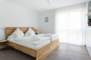 ein weißes Schlafzimmer mit einem großen Bett mit weißen Kissen in der Unterkunft Kurviertel Wohnung IV in Überlingen