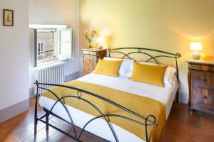 Un dormitorio con una cama con almohadas amarillas y una ventana en Locanda Quattro Vesta, en San Casciano dei Bagni