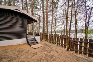 a wooden cabin with a staircase next to a fence at Sielanka Mazury in Szczytno