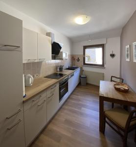 特拉本特拉巴赫的住宿－Ferienweingut Göbel，厨房配有白色橱柜和木桌