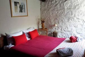 a bedroom with a large bed with red pillows at Salto do Lobo - Montain houses with private river in Penhas da Saúde