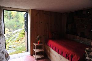 a bedroom with a bed and a large window at Salto do Lobo - Montain houses with private river in Penhas da Saúde