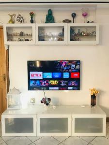 a flat screen tv on a wall with a white desk at Spacious House 15min to Canary Wharf/O2/Excel/Central London in London