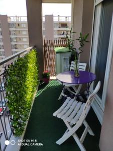 un balcón con una mesa púrpura y sillas. en appartement marseille velodrome, en Marsella